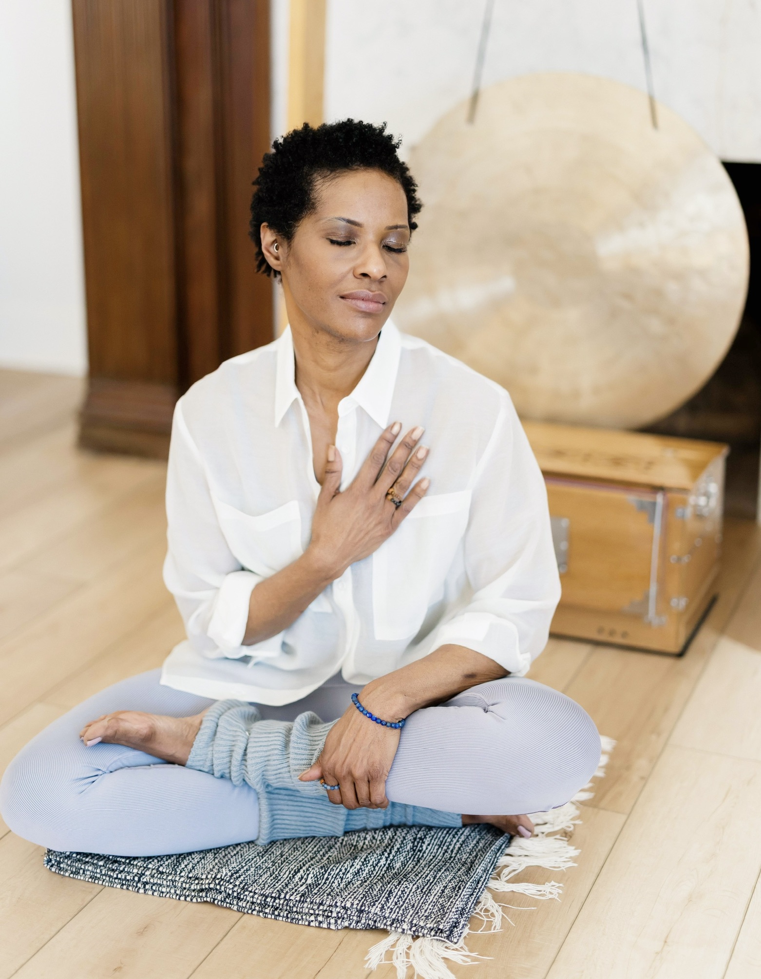 Michelle meditating with her hand on her heart beside a gong