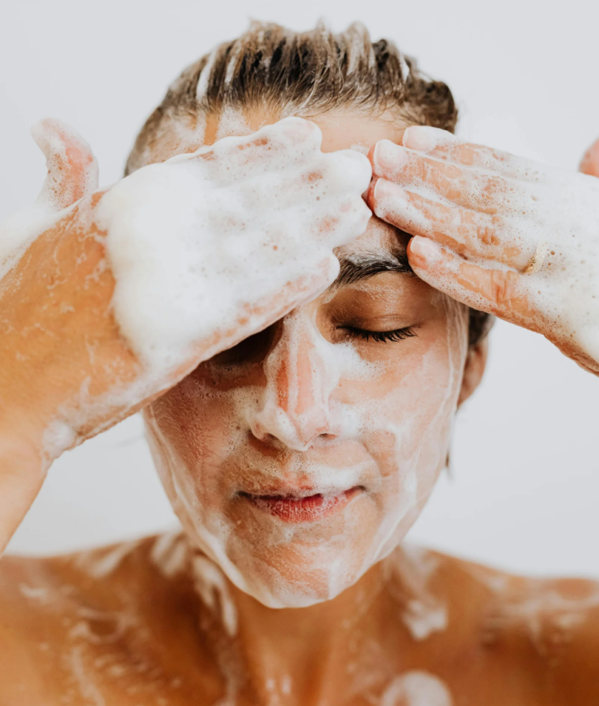 Woman with closed eyes gently massaging foaming cleanser over her face.
